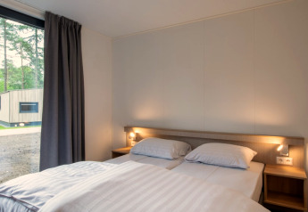 Chambre du Tiny House 2 à Bospark 't Wolfsven aux Pays-Bas, avec lit double et grande fenêtre.