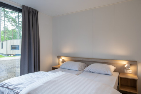 Camera da letto della Tiny House 2 al Bospark 't Wolfsven nei Paesi Bassi con letto matrimoniale e finestra.