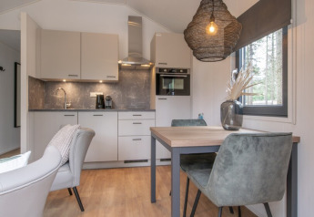Cuisine moderne et coin repas chaleureux d'une tiny house au Bospark 't Wolfsven, aux Pays-Bas.
