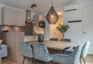 Espace salle à manger et salon moderne avec table en bois et chaises en velours au Timber Cottage 6.