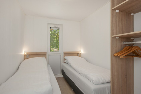 Twin bedroom with two beds and open wardrobe in Lodge 6 at Bospark 't Wolfsven, the Netherlands.