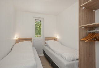Twin bedroom with two beds and open wardrobe in Lodge 6 at Bospark 't Wolfsven, the Netherlands.