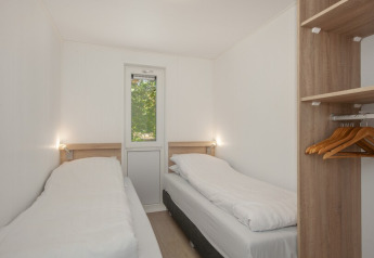Schlafzimmer in Lodge 6 mit zwei Einzelbetten und offenem Kleiderschrank im Bospark 't Wolfsven, Niederlande.