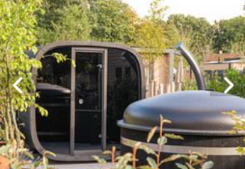 Area esterna della lodge ‘Cannenburch’ Deluxe nel Veluwe park de Bosgraaf, Paesi Bassi, con sauna e vasca.