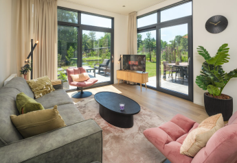 Soggiorno della lodge "Cannenburch" Deluxe al parco Veluwe de Bosgraaf, Paesi Bassi, con arredamento moderno e vista giardino.