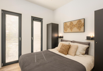 Camera moderna alla lodge 'Cannenburch' Deluxe, Veluwe park de Bosgraaf, con letto matrimoniale e decorazioni sobrie.
