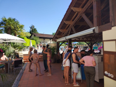 Gasten ontspannen en staan in de rij bij de buitenbar van Domaine Papillon vakantiepark in Occitanië, Frankrijk.