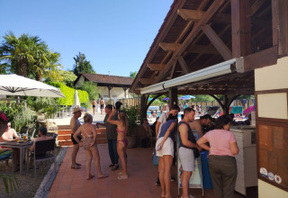Gasten ontspannen en staan in de rij bij de buitenbar van Domaine Papillon vakantiepark in Occitanië, Frankrijk.