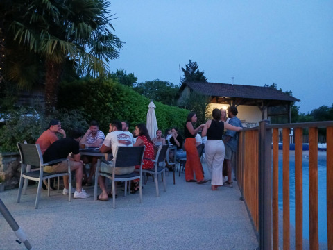 Groep mensen geniet van een avond buiten bij Domaine Papillon vakantiepark in Occitanie, Frankrijk, bij het zwembad.