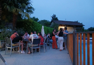 Groep mensen geniet van een avond buiten bij Domaine Papillon vakantiepark in Occitanie, Frankrijk, bij het zwembad.