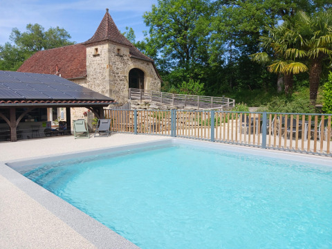 Buitenzwembad met historisch stenen gebouw bij Domaine Papillon vakantiepark in Occitanië, Frankrijk.