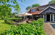 Buitenzitje aan Outdoors Holten vakantiepark in Overijssel, Nederland, met veel groen en gezellig terras.