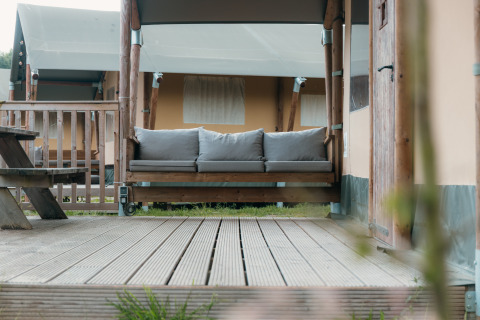 Terrasse en bois avec canapé devant une tente safari de luxe au Holiday park Sallandshoeve, Pays-Bas.