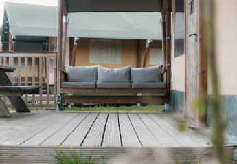 Terrasse en bois avec canapé devant une tente safari de luxe au Holiday park Sallandshoeve, Pays-Bas.