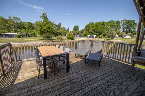 Grande terrasse en bois avec table, chaises et transats au bord du lac, Luxury Safari tent, Holiday park Sallandshoeve.