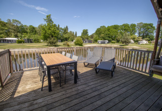 Grande terrasse en bois avec table, chaises et transats au bord du lac, Luxury Safari tent, Holiday park Sallandshoeve.