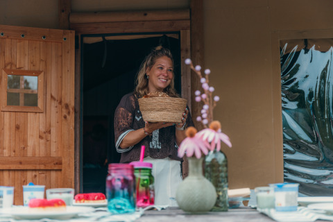 Femme tenant un panier devant une tente safari de luxe au Holiday park Sallandshoeve aux Pays-Bas.