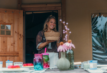 Mujer con cesta frente a una tienda safari de lujo en Holiday park Sallandshoeve, Países Bajos.
