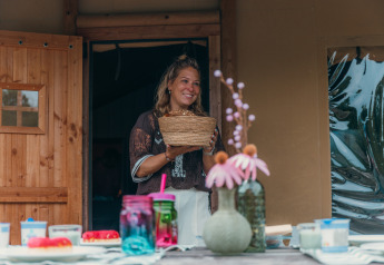 Femme tenant un panier devant une tente safari de luxe au Holiday park Sallandshoeve aux Pays-Bas.