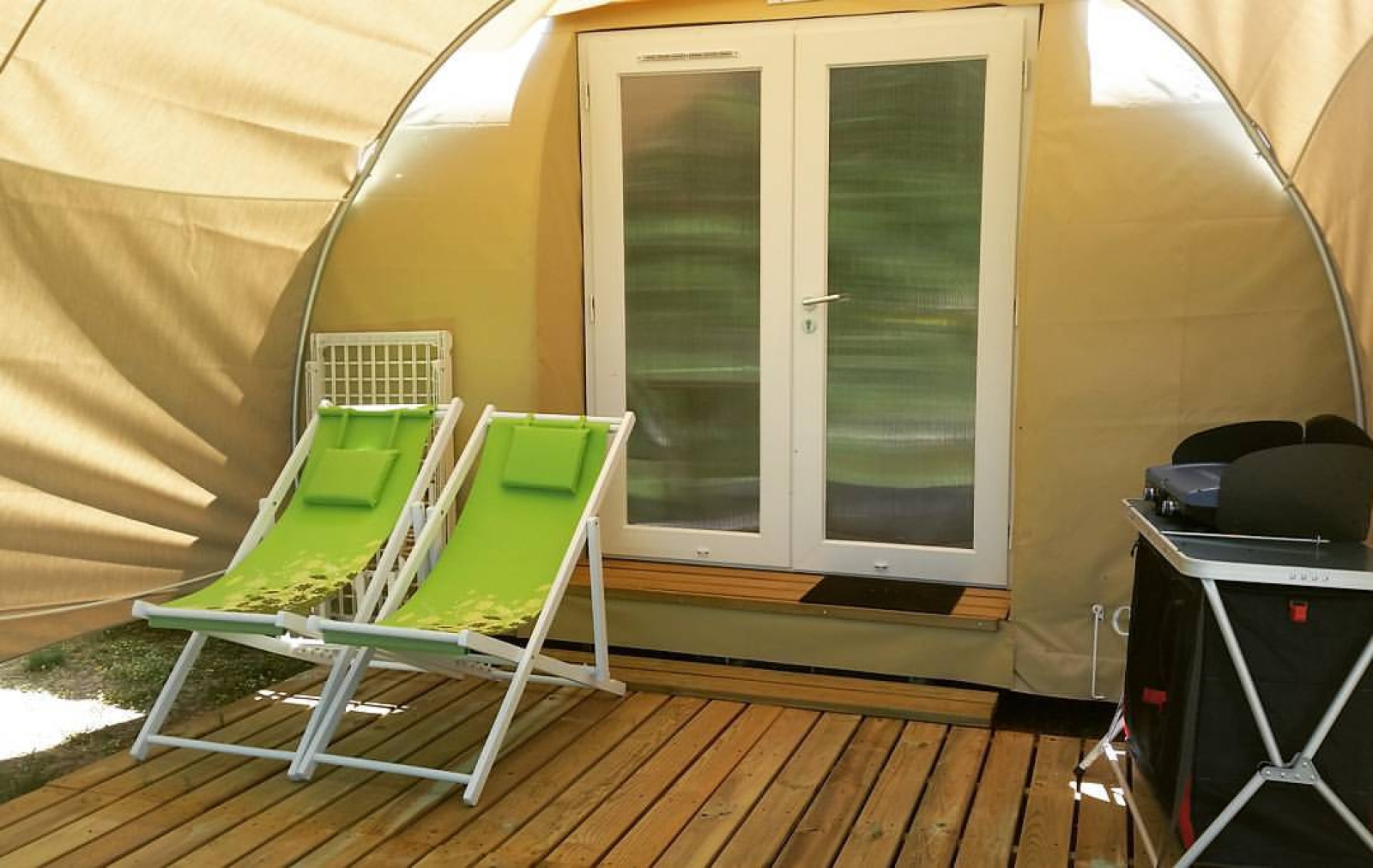 Twee groene ligstoelen op een houten terras voor een Coco Sweet safaritent op Flower Camping Le Pont du Tarn.
