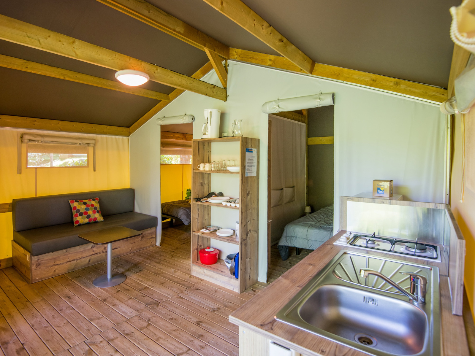 Binnenaanzicht van de Freeflower Comfort safaritent bij Flower Camping Le Pont du Tarn met keuken en bank.