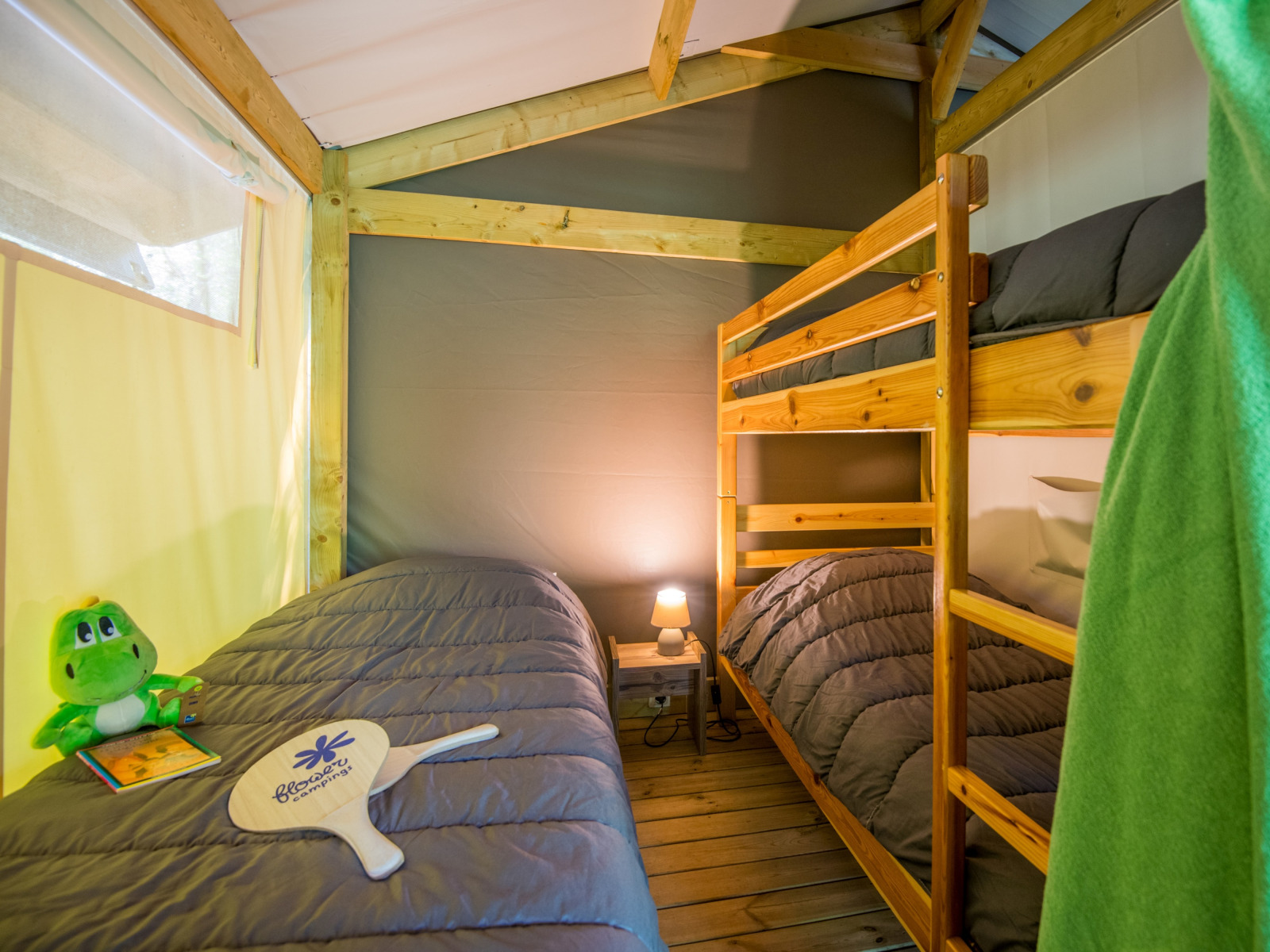 Binnenaanzicht van een safaritent met stapelbed en eenpersoonsbed bij Flower Camping Le Pont du Tarn in Frankrijk.