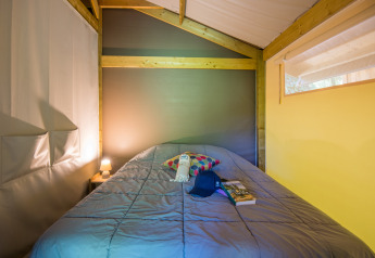 Indretning af et hyggeligt soveområde i et Freeflower Comfort safaritelte på Flower Camping Le Pont du Tarn.
