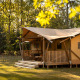 Safari-Zeltunterkunft De Heide Tent im Wald, mit Holzterrasse und Sitzgelegenheiten im Sonnenlicht.