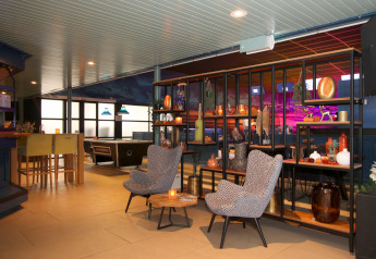 Hotellets loungeområde med moderne møbler, poolbord og smagfuld dekoration, hyggelig belysning.
