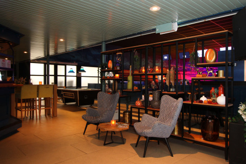 Modern lodge lounge area with cozy armchairs, decorative shelf, pool table, and warm ambient lighting.