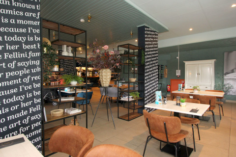 Modernes Restaurant in einer Lodge mit braunen Stühlen, weißen Tischen und dekorativen Pflanzen.