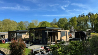 Vista exterior de la cabaña Cannenburch Deluxe con bañera de hidromasaje privada, sauna y terraza elegante.