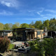 Buitenzicht op de Cannenburch Deluxe lodge met hot tub, sauna, terras en omgeven door groen en bos.