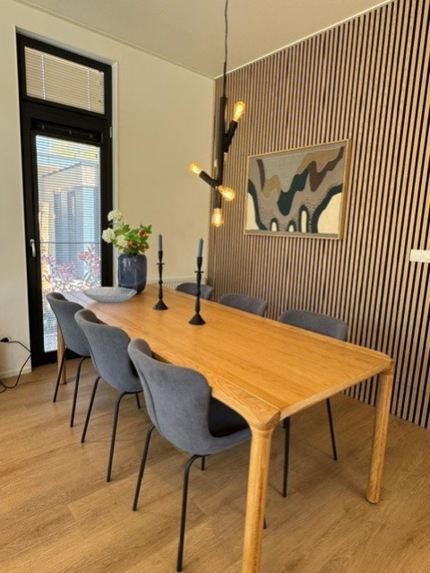 Eettafel met zes stoelen, houten blad en moderne verlichting in lodge 'Cannenburch', Veluwe park de Bosgraaf, Nederland.