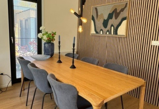 Eettafel met zes stoelen, houten blad en moderne verlichting in lodge 'Cannenburch', Veluwe park de Bosgraaf, Nederland.