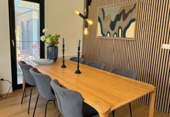 Salle à manger avec table en bois, six chaises grises, suspension moderne dans le lodge «Cannenburch», Veluwe park de Bosgraaf, Pays-Bas.