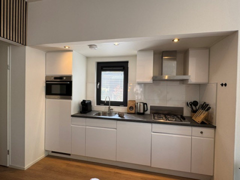Moderne keuken in ‘Cannenburch’ Deluxe lodge, Veluwe park de Bosgraaf, met raam en keukenapparaten.
