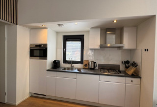 Moderne keuken in ‘Cannenburch’ Deluxe lodge, Veluwe park de Bosgraaf, met raam en keukenapparaten.