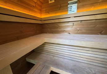 Indvendig udsigt til en moderne træsauna med belysning på Cannenburch Deluxe, Veluwe park de Bosgraaf.