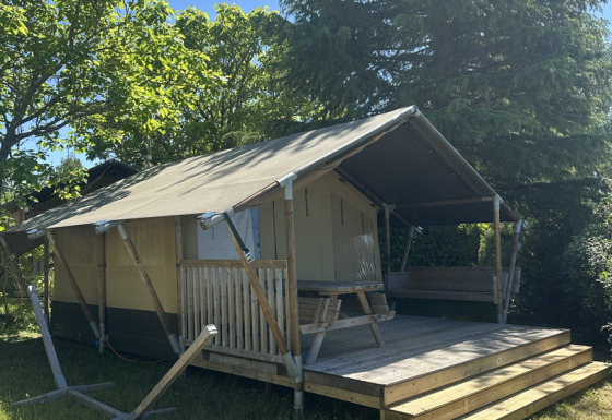 Safari tent named Compact with private sanitary facilities, wooden terrace, and picnic table outdoors.