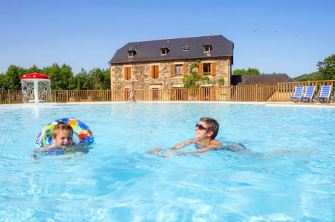 Due persone si divertono nella piscina del Seasonova Camping Les Rives d'Olt et Aubrac in Occitania, Francia.