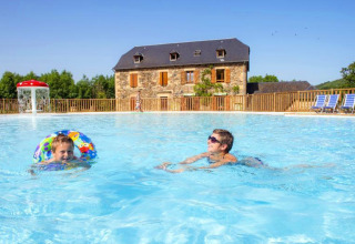Deux personnes profitent de la piscine au Seasonova Camping Les Rives d'Olt et Aubrac, situé en Occitanie, France.