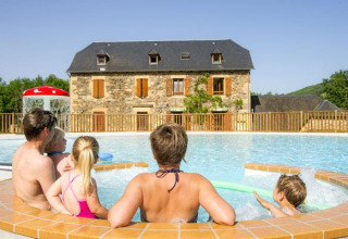 Famiglia che si rilassa in piscina al Seasonova Camping Les Rives d'Olt et Aubrac in Occitania, Francia.
