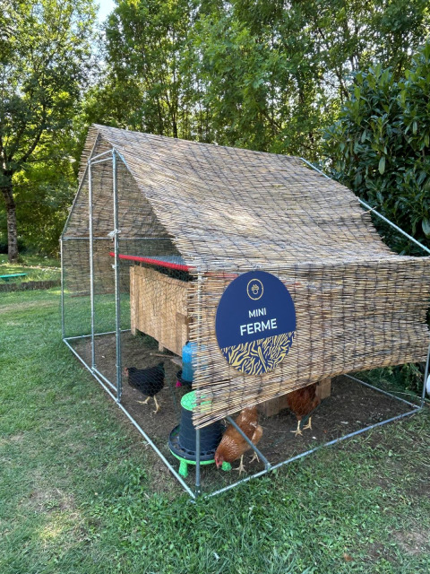 Pollaio con il cartello 'Mini Ferme' in un parco verde presso Seasonova Camping Les Rives d'Olt et Aubrac, Francia.