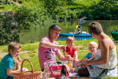 Famiglia fa un picnic vicino al fiume al Seasonova Camping Les Rives d'Olt et Aubrac in Occitania, Francia.