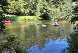 Due canoe rosse su un fiume tranquillo circondato dal verde al Seasonova Camping Les Rives d'Olt in Occitania, Francia.