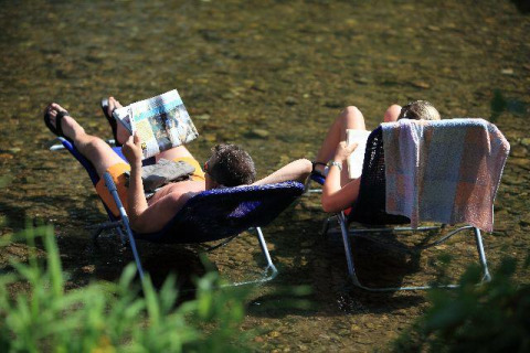 Due persone si rilassano su sedie in un fiume al Seasonova Camping Les Rives d'Olt et Aubrac, Occitanie.
