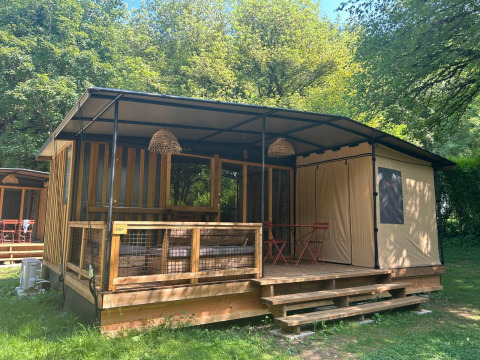 Tiny house Tiny Lodge con veranda coperta, dettagli in legno e immersa nel verde tra gli alberi.