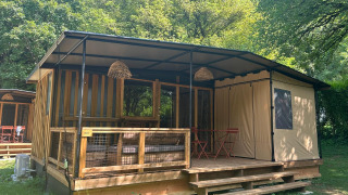 Tiny house Tiny Lodge con veranda coperta, dettagli in legno e immersa nel verde tra gli alberi.