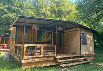 Tiny Lodge tiny house with a covered veranda, wooden accents, surrounded by trees and lush greenery.